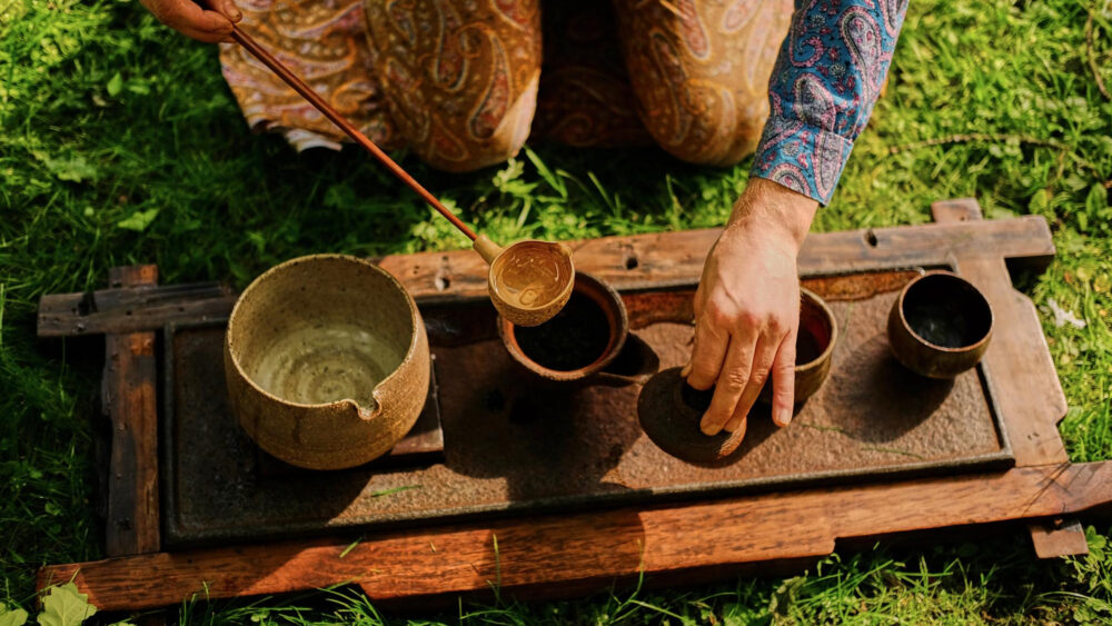 A traditional tea-drinking scene in an open natural setting with a warm and culturally rich ambiance.