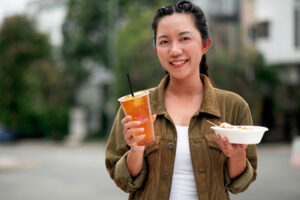 a woman holding a prendjak tea cup and a bowl of food