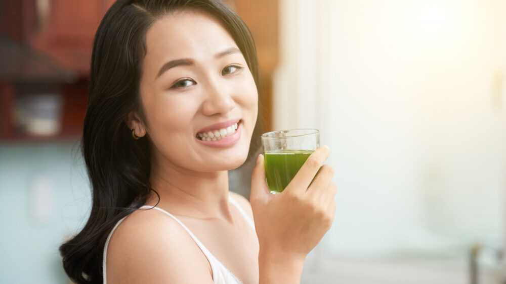 an asian woman holding a glass of green tea