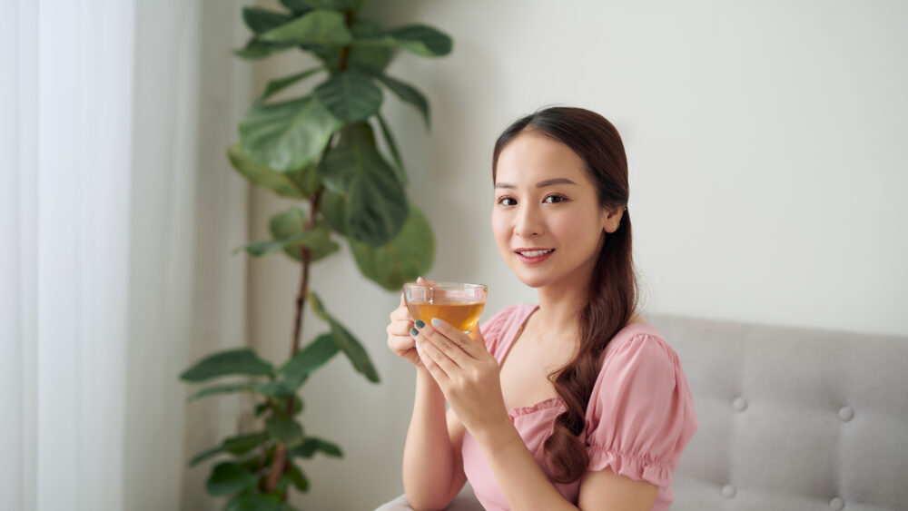 A woman pouring warm tea into glasses, capturing a calm moment and the daily health benefits of drinking tea